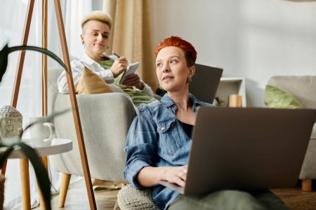 Photo for A lesbian couple with short hair sits on a couch, each engrossed in their laptop screens. - Royalty Free Image