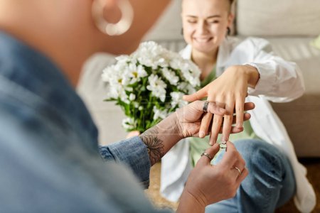 Ein rührender Moment, als eine Frau einem anderen liebevoll einen Ring an den Finger legt, der ihr Engagement und ihre Liebe symbolisiert.
