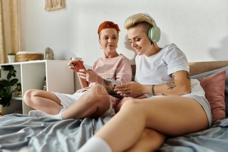 Photo for Two women in a bedroom playing games together, enjoying a cozy and fun evening. - Royalty Free Image