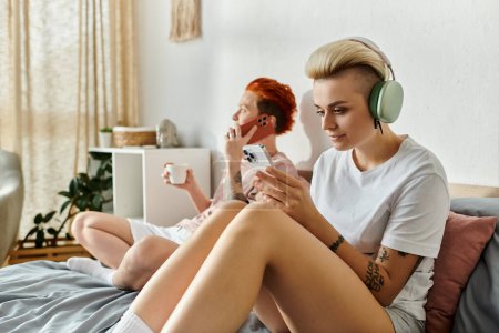 Ein lesbisches Paar mit kurzen Haaren sitzt auf einem Bett, durch Kopfhörer in Musik vertieft und verkörpert die Essenz des LGBT-Lebensstils.