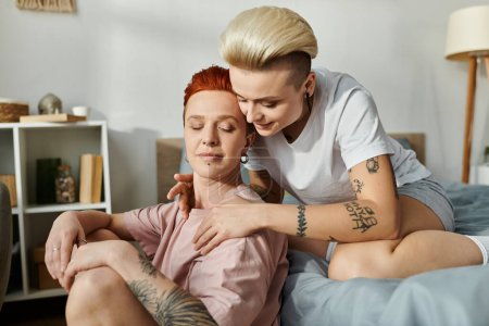 A lesbian couple with short hair embracing each other warmly while lying on a bed, showcasing love and closeness.