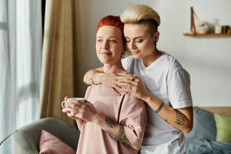 Zwei Frauen mit kurzen Haaren umarmen sich in einem gemütlichen Wohnzimmer, was die Schönheit der Liebe in einem LGBT-Lebensstil widerspiegelt.