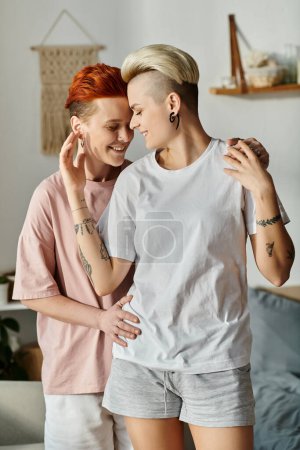 Foto de Dos mujeres con el pelo corto abrazándose en una cálida sala de estar, mostrando amor y apoyo en el estilo de vida LGBT. - Imagen libre de derechos