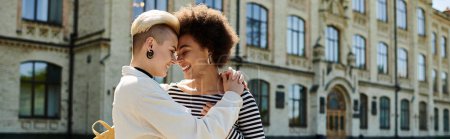 Photo for Two young women in stylish attire sharing a warm hug in front of an old building on a university campus. - Royalty Free Image