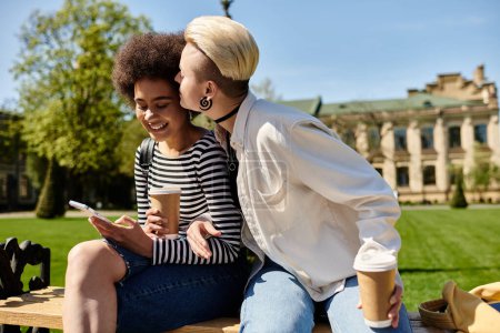 Two young women in stylish attire are seated on a park bench, deep in conversation, surrounded by greenery.