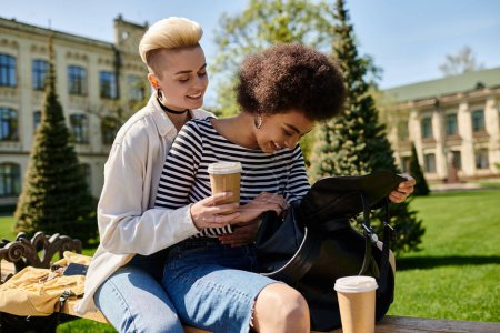 Zwei stylische junge Frauen entspannen sich auf einer Bank und nippen an einem Kaffee in einem ruhigen Moment.