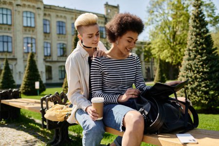 Ein multikulturelles lesbisches Paar in stilvoller Kleidung sitzt zusammen auf einer Bank in einem Park und genießt die Gesellschaft der anderen.