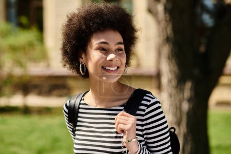 Young woman with afro hair leisurely walking through a parks serene atmosphere.