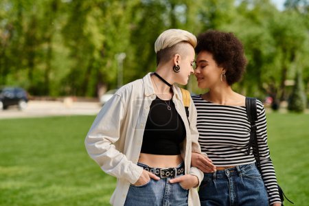 Foto de Una pareja lesbiana multicultural, ambas jóvenes estudiantes, pasean con estilo por un parque cerca del campus universitario. - Imagen libre de derechos