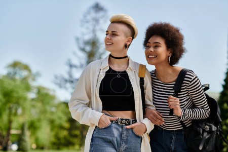 Foto de Dos mujeres jóvenes, una pareja lesbiana multicultural, caminando juntas en un parque - Imagen libre de derechos