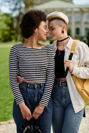 Foto de Dos mujeres jóvenes en jeans y camisetas a rayas posan al aire libre. - Imagen libre de derechos
