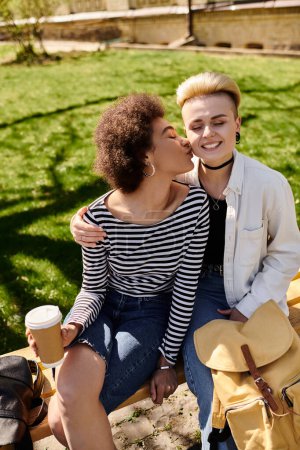 Téléchargez les photos : Deux jeunes filles partagent un baiser d'amour sur un banc de parc, entouré par l'ambiance paisible de la nature. - en image libre de droit