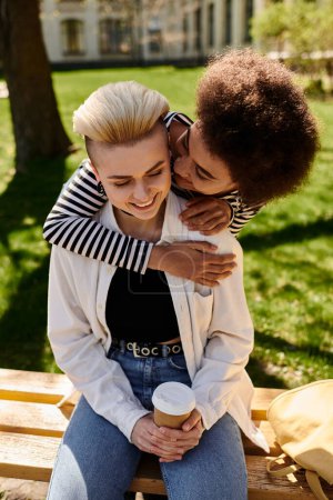 Zwei Frauen, die sich herzlich umarmen, sitzen in einem zärtlichen Moment der Liebe und Zuneigung auf einer Bank.