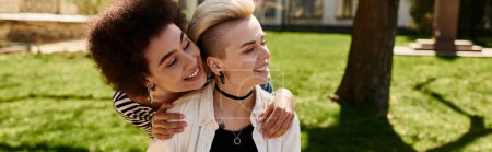 Two young female students, a multicultural lesbian couple, embrace each other warmly in a vibrant park setting.