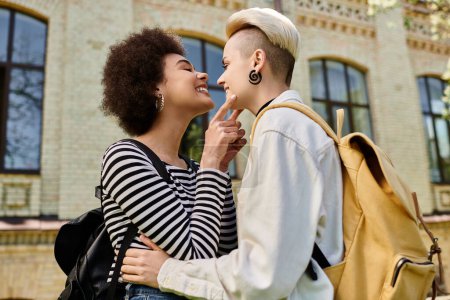 Un momento capturado donde dos mujeres jóvenes, pareja lésbica multicultural, abrazándose en un cálido abrazo fuera de un edificio universitario.
