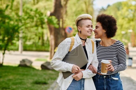 Deux jeunes femmes en tenue décontractée bavardent dans un parc, se connectant dans un environnement extérieur paisible près d'un campus universitaire.