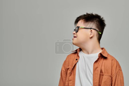 A little boy with Down syndrome wearing glasses looking away.
