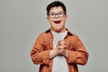 A little boy with Down syndrome, sporting glasses, smiles brightly.
