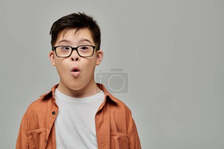 A charming little boy with Down syndrome making a silly face while wearing glasses.