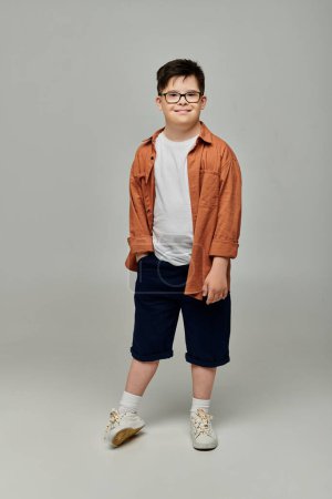 Ein süßer Junge mit Down-Syndrom in Brille und Shorts posiert für ein Porträt