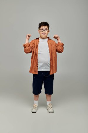Junge mit Down-Syndrom posiert mit Brille für die Kamera.