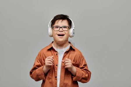 A joyful little boy with Down syndrome wears headphones, beaming with a smile.