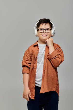 Ein kleiner Junge mit Down-Syndrom posiert mit Kopfhörern für die Kamera.