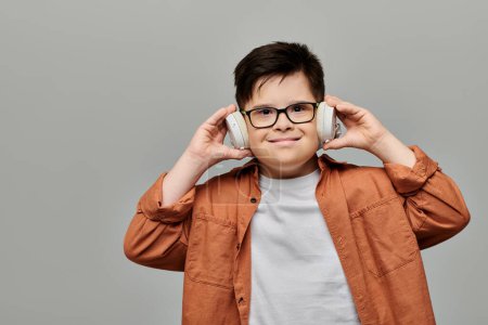 Photo for Little boy with boy with Down syndrome with glasses listening to music. - Royalty Free Image