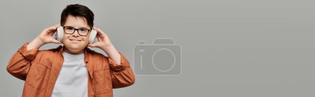Photo for Little boy with Down syndrome with glasses covering ears with hands. - Royalty Free Image