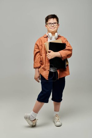 Kleiner Junge mit Down-Syndrom mit Brille, in der Hand einen Ordner.