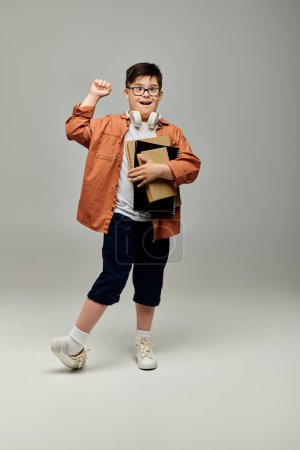 A little boy with Down syndrome holding a books and posing.