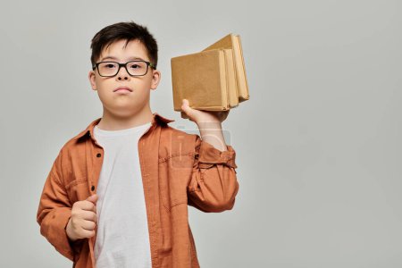 little boy with Down syndrome holding a stack of books.