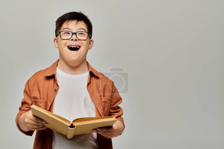 Un niño con síndrome de Down en gafas lee un libro intensamente.
