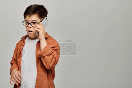 little boy with Down syndrome with glasses chatting on phone.