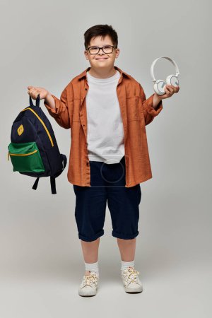 little boy with Down syndrome with backpack and headphones.