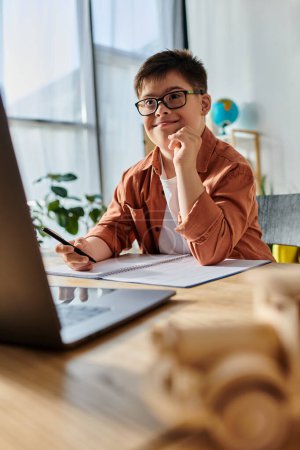 adorable boy with Down syndrome in glasses studying with laptop at desk