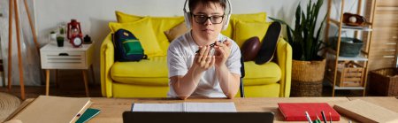 Téléchargez les photos : A boy with Down syndrome with glasses works on his laptop at a desk. - en image libre de droit