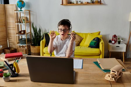 Ein Junge mit Down-Syndrom sitzt am Schreibtisch und konzentriert sich auf die Benutzung eines Laptops.