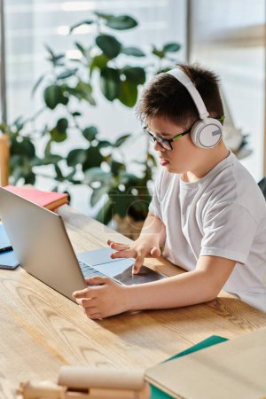 A adorable boy with Down syndrome wearing headphones is engrossed in using a laptop at home.