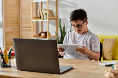Foto de Adorable chico con síndrome de Down con gafas inmersas en actividades de ordenador portátil en casa. - Imagen libre de derechos