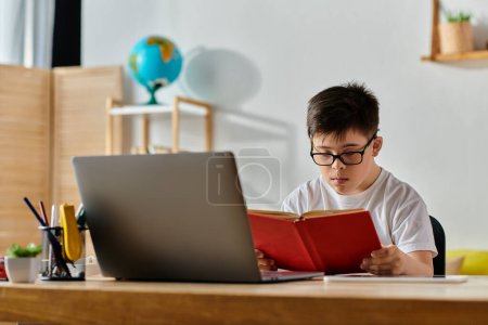 Junge mit Down-Syndrom lernt mit Laptop auf Schreibtisch.