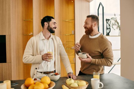 Téléchargez les photos : A gay couple happily eating breakfast in a modern kitchen. - en image libre de droit