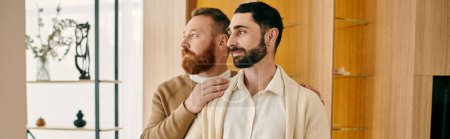 Zwei glückliche Männer stehen nebeneinander in einem modernen Wohnzimmer und zeigen Liebe und Zweisamkeit in ihrer LGBT-Beziehung.