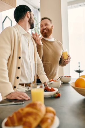 Téléchargez les photos : Deux hommes gays heureux prennent le petit déjeuner ensemble dans une cuisine moderne, partageant un moment d'amour et de compagnie. - en image libre de droit