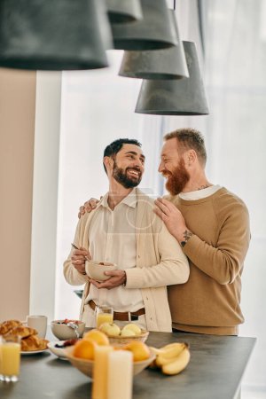 Una feliz pareja gay se abraza en un cálido abrazo en una cocina moderna, celebrando su amor y vínculo.
