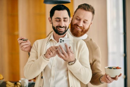 Deux hommes barbus regardant joyeusement le contenu sur un téléphone portable, partageant un moment d'intimité et de connexion.