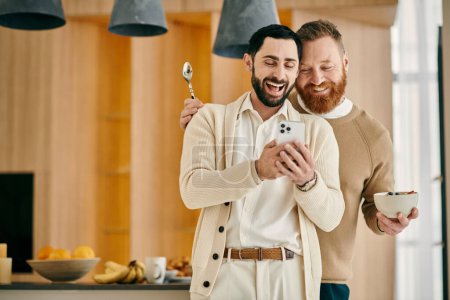 Dos hombres sonriendo felizmente mientras sostienen un teléfono celular en un moderno apartamento.