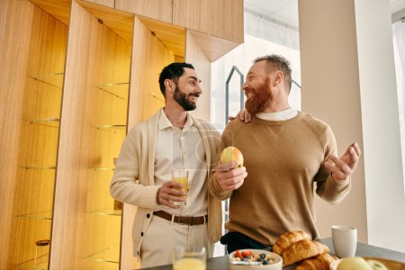 Foto de Dos hombres felices, una pareja gay, disfrutando del desayuno en una cocina moderna. - Imagen libre de derechos