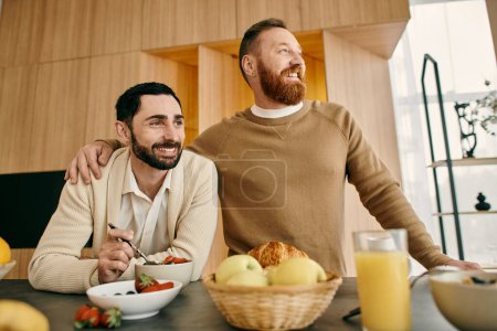 Zwei bärtige Männer frühstücken gemeinsam in einer gemütlichen Küche und präsentieren ihre Verbundenheit und gemeinsame Momente.
