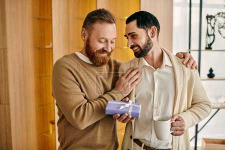 Foto de Dos hombres intercambian alegres cajas de regalo en un apartamento moderno, celebrando el amor y la compañía. - Imagen libre de derechos